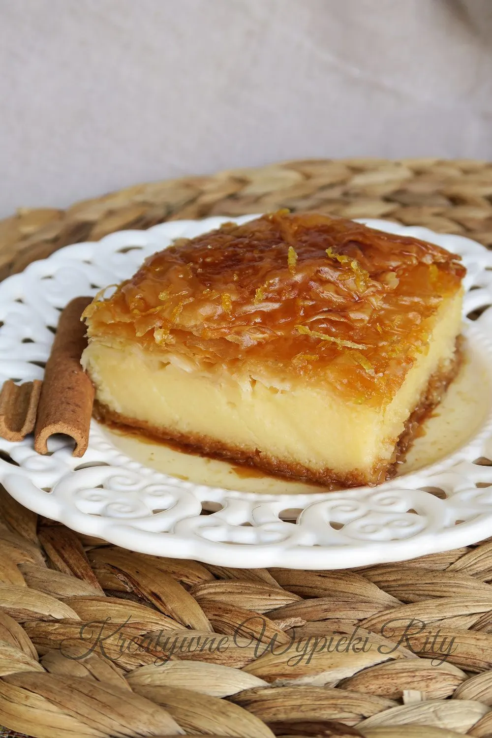 Kawałek greckiego ciasta Galaktoboureko na talerzu, widoczne chrupiące warstwy ciasta filo i gęsty krem z kaszy manny.